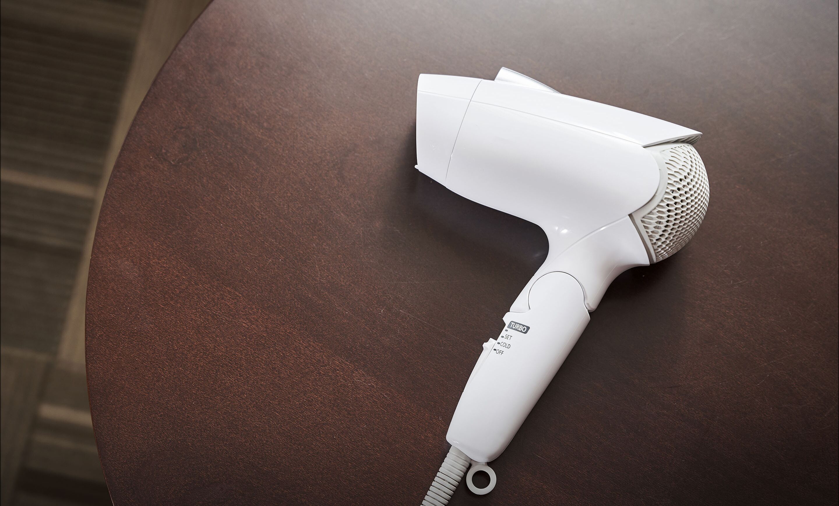 A white hair dryer on a round table.