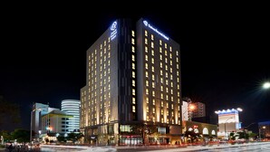 Een hoog hotel met meerdere verdiepingen, verlichte ramen en een opvallend bord bovenaan.