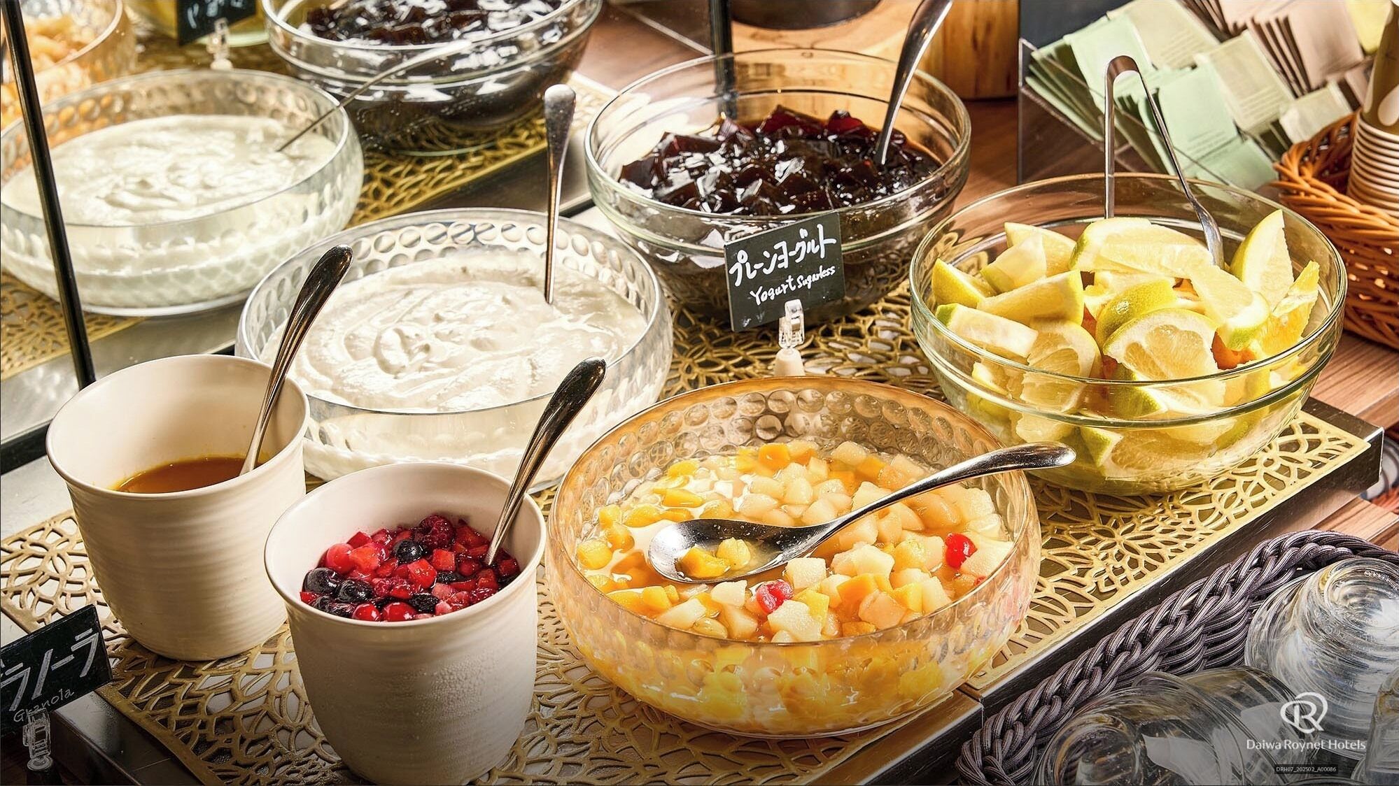 A buffet with various food items including yogurt, fruit, and a dessert.