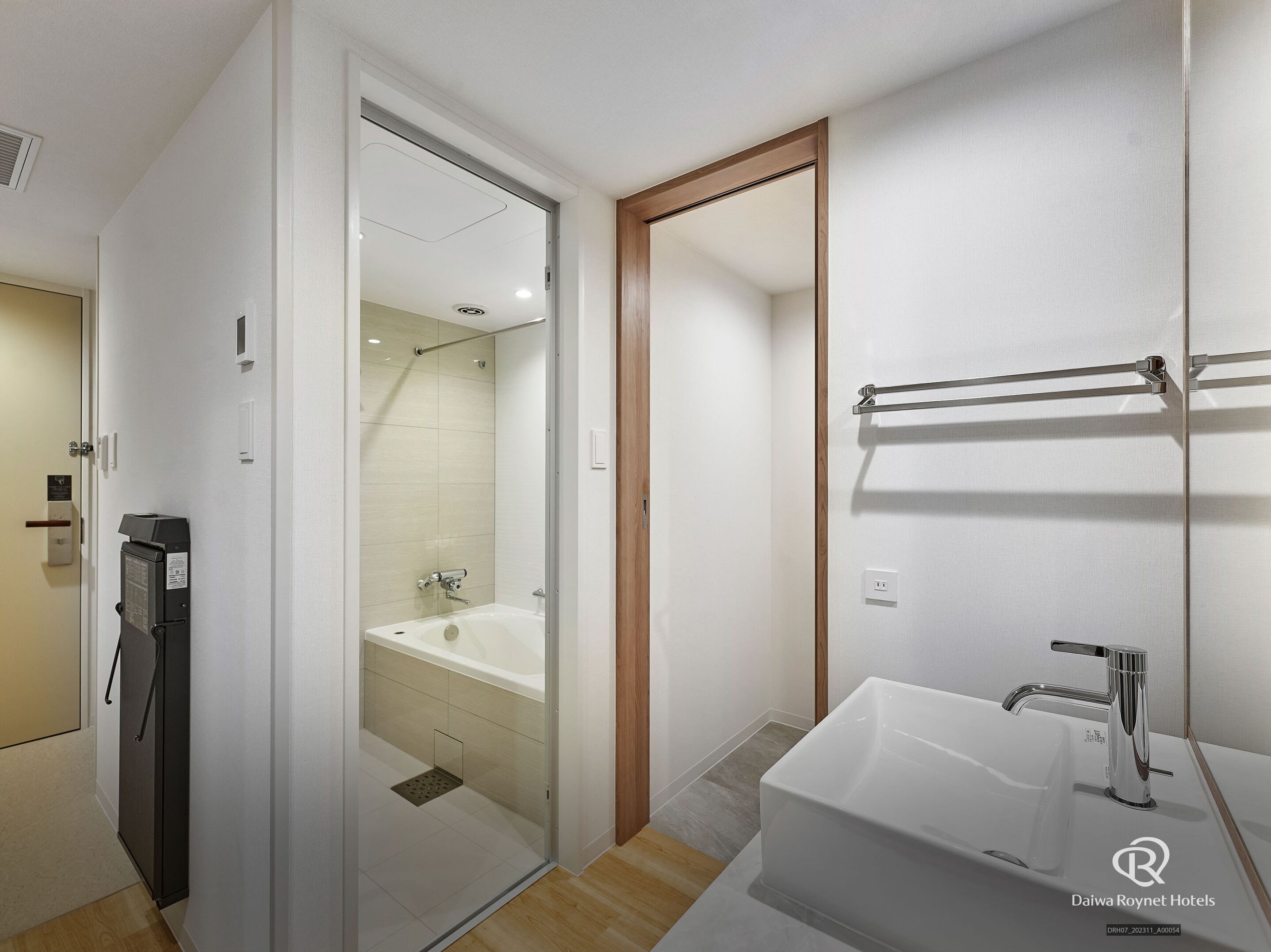 A modern bathroom with a glass shower enclosure, a white bathtub, and a sink with a chrome faucet.