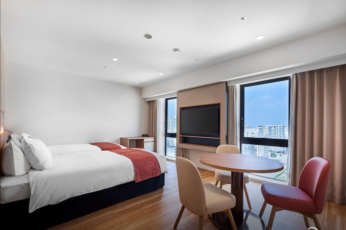 Een hotelkamer met een bed, een bureau, een televisie en een eettafel met stoelen.