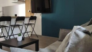 A modern living room with a grey sofa, a coffee table with a plant, and a TV mounted on a teal wall. - Village house with exterior (Lambesc)