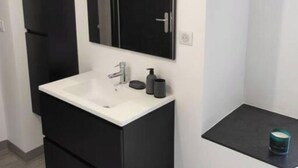 A modern bathroom with a black vanity, a white sink, and a mirror above it. - Village house with exterior (Lambesc)