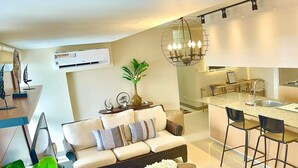 A modern living room with a sofa, coffee table, and a dining area with chairs.