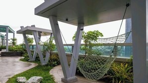 A rooftop garden with modern architecture, including a hammock and seating areas.