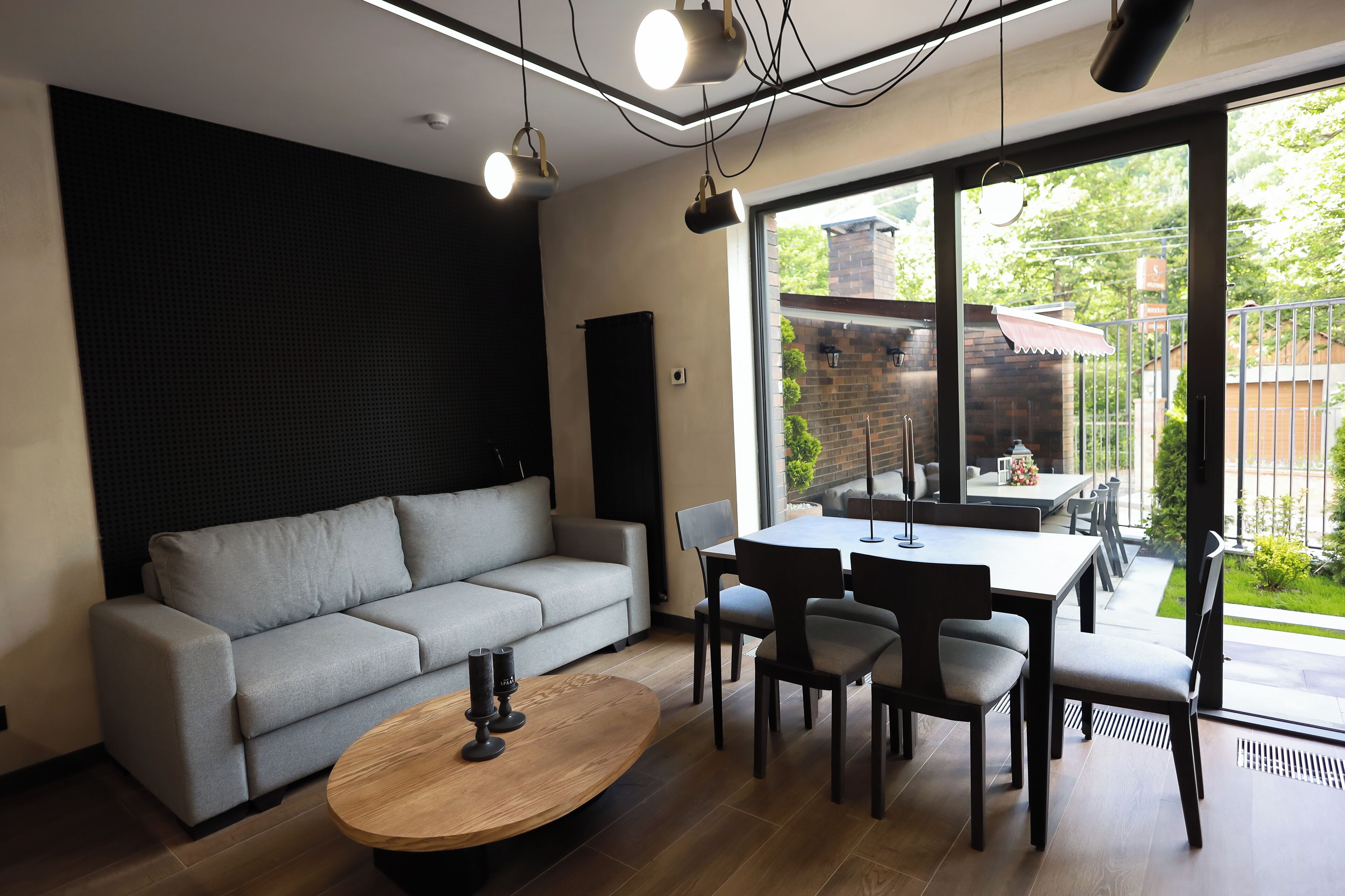 A modern living room with a grey sofa, a wooden coffee table, and a dining area with a table and chairs.