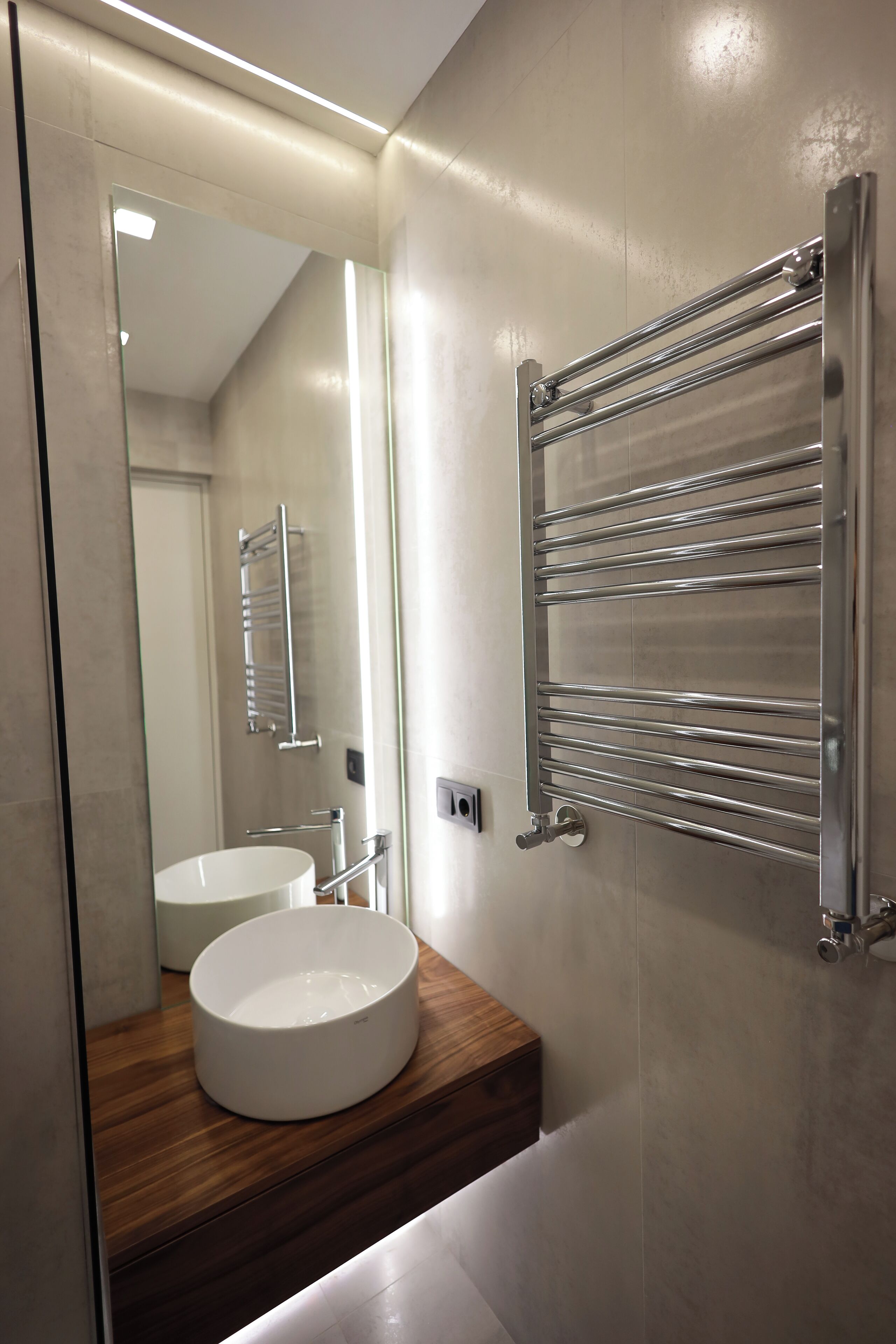 Een moderne badkamer met een rond wastafel, een houten aanrechtblad en een douchecabine van glas.
