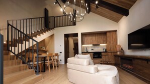 A modern living room with a staircase, a sofa, a dining area, and a kitchen. - Epoca (Tsaghkadzor)