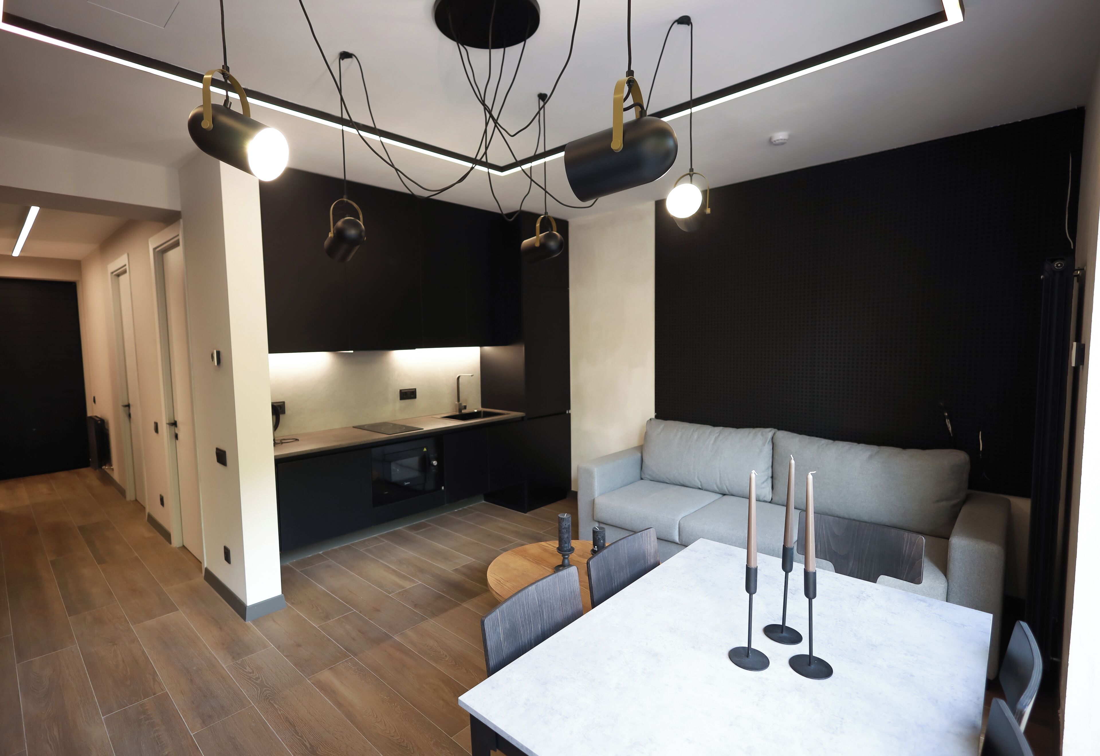A modern kitchen with a dining area, a sofa, and a table with candles.