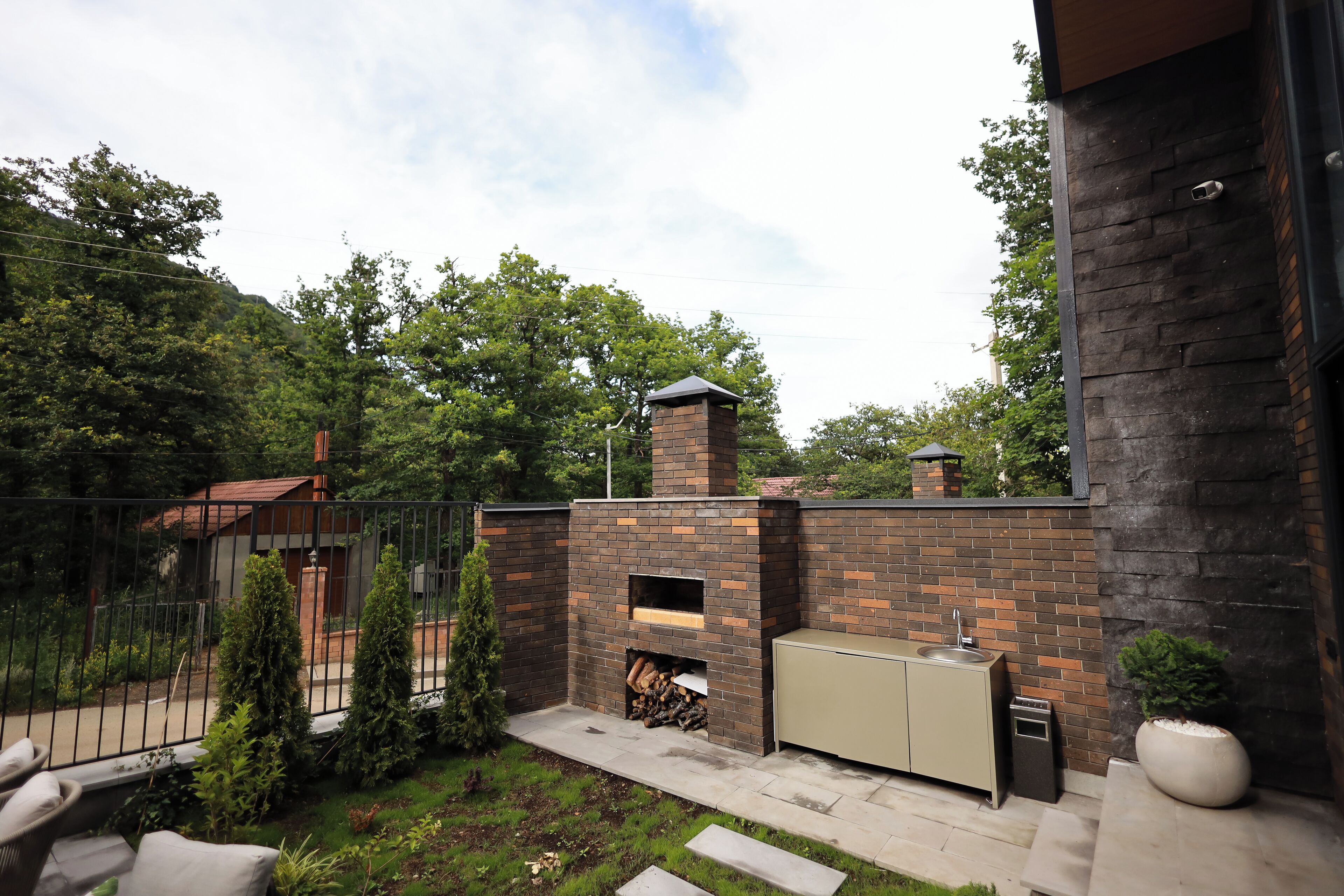 A backyard with a brick fireplace, outdoor sink, and a small garden area.