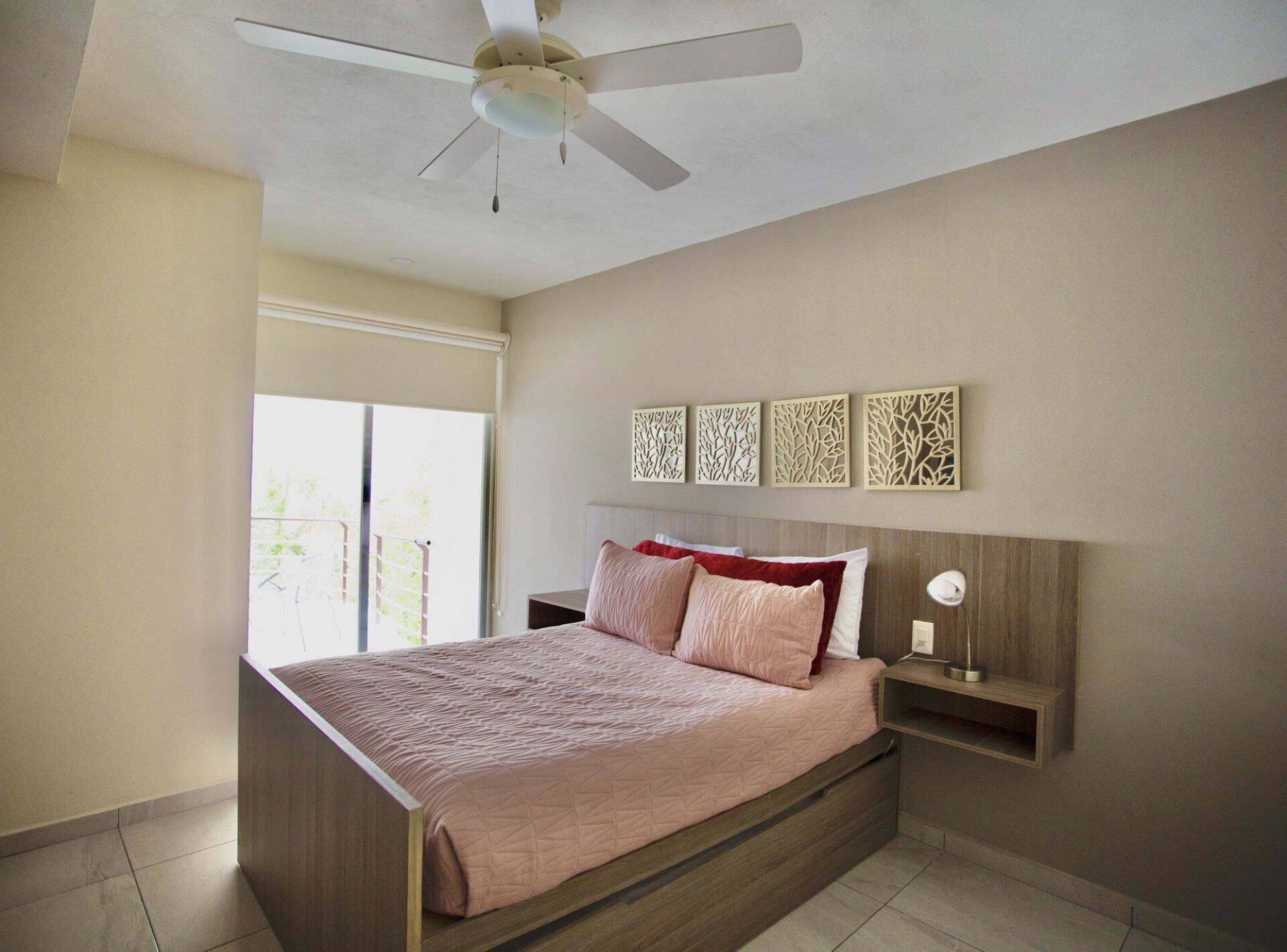 A bedroom with a bed, a ceiling fan, a window, and wall art.