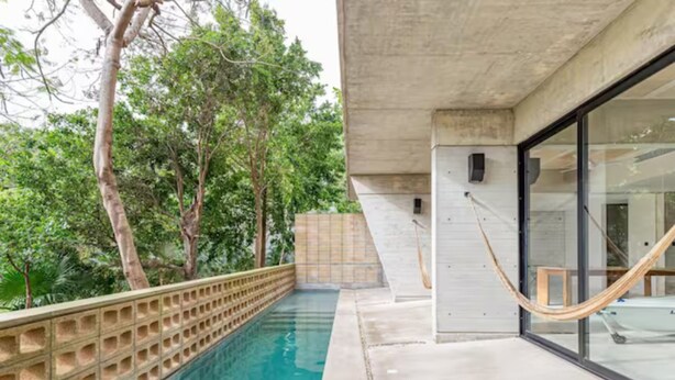 A swimming pool with a concrete deck, surrounded by trees. - Incredible Loft With Pool (Cancún)