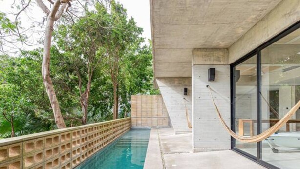 A swimming pool with a concrete deck, surrounded by trees. - Fresh Large Loft With Pool (Cancún)