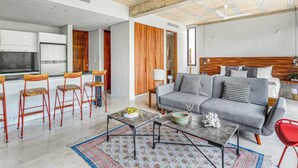A modern living room with a grey sofa, red chairs, a coffee table, and a patterned rug.