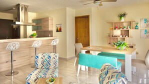 Une cuisine moderne dotée d’une cuisinière intégrée, d’un coin repas avec une table et des chaises en bois, et d’un ventilateur de plafond.