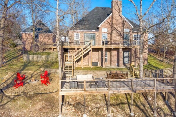 A large brick house with a deck, outdoor seating, and a fire pit.