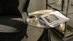 Una mesa de vidrio con una taza de café, una revista y un plato de galletas.