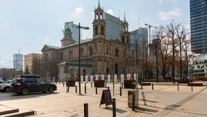 Un edificio histórico con una imponente torre de reloj, rodeado de modernos rascacielos.