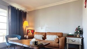 Una sala de estar con un sofá, una mesa de centro, una lámpara, una silla y una mesita auxiliar con una planta.