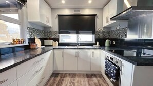 Una cocina moderna con armarios blancos, encimera negra, horno empotrado y ventana con vistas.