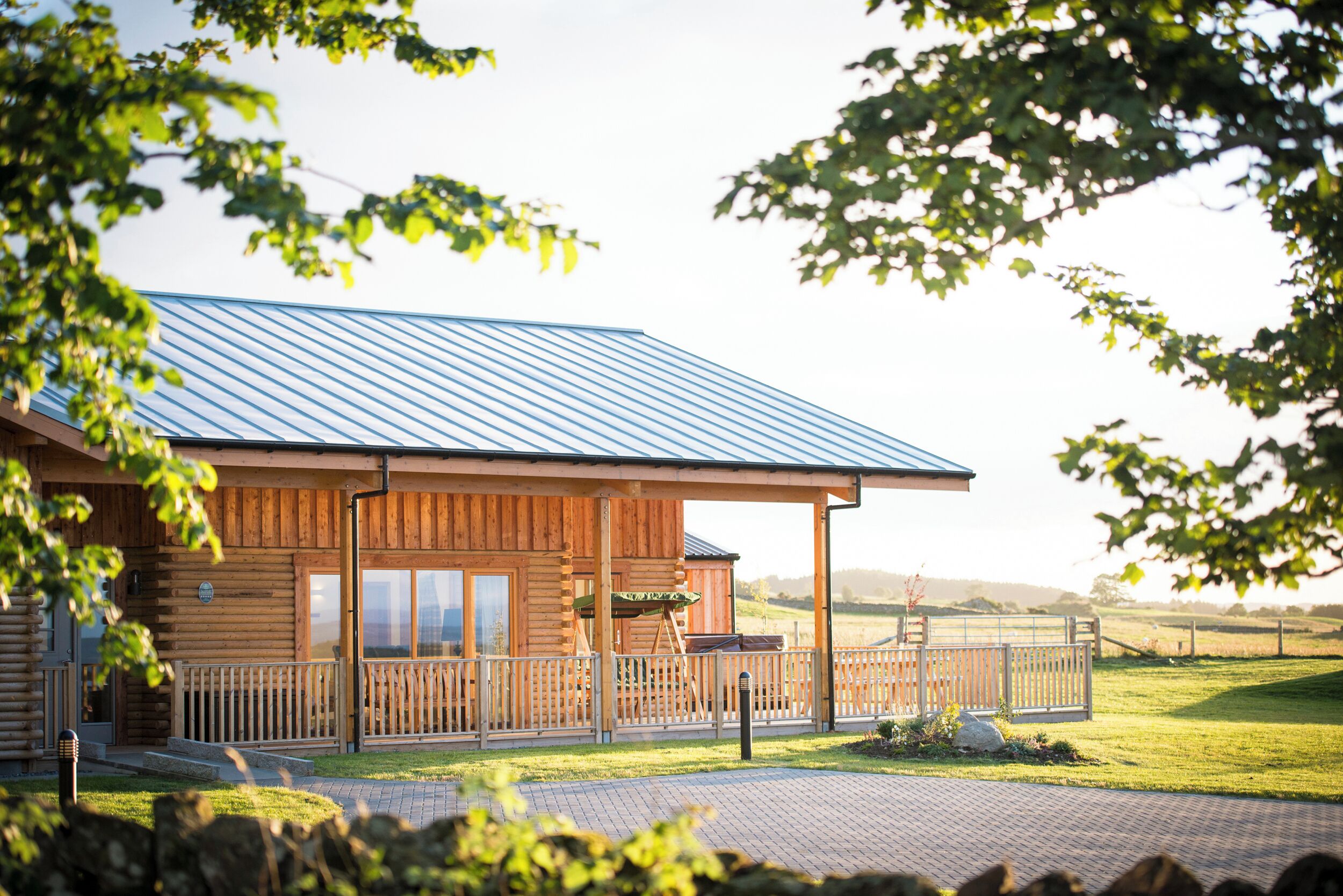 A wooden cabin with a metal roof, a porch, and a fenced outdoor area.