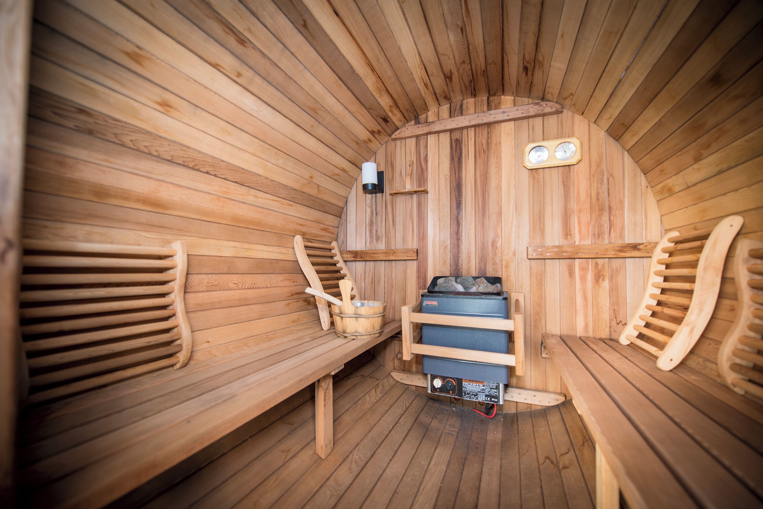 Una sauna con bancos de madera, un calentador y un panel de control.