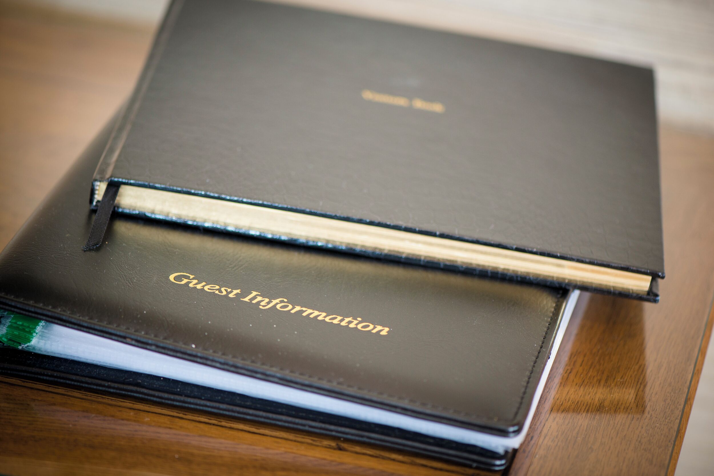 A stack of black books with the top book labeled "Guest Information".