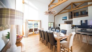 Un comedor amplio con una mesa y sillas de madera, un candelabro y vistas al exterior.
