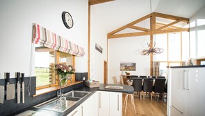 Una cocina moderna con techo de madera, un ventanal grande y una zona de comedor con vistas.