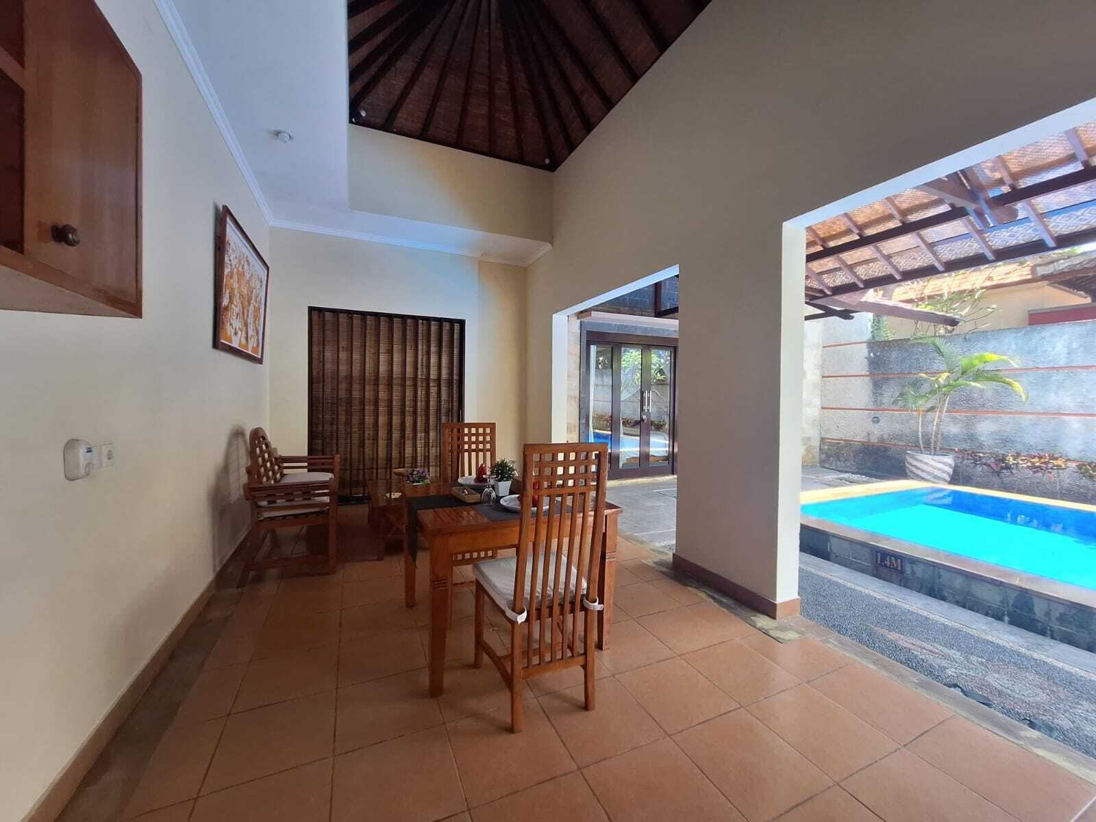 A dining area with wooden furniture and a view of a swimming pool.