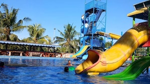 Een waterpark met een grote gele glijbaan en een blauwe watertoren.