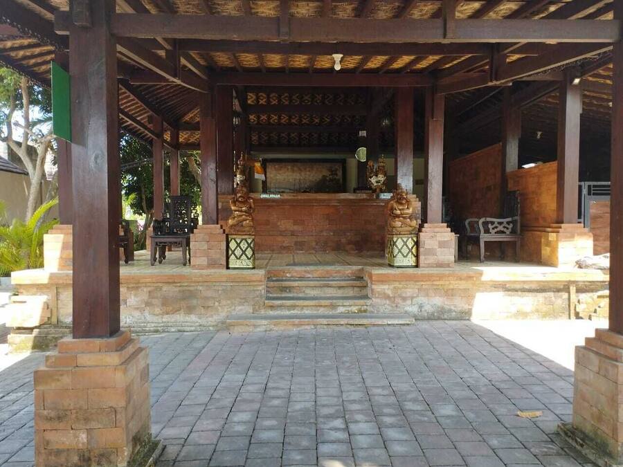 A covered pavilion with a central altar, steps leading up to it, and a brick-paved area.