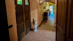 A hallway with wooden doors, a tiled floor, and a dining area in the background. - Apartment Ca' Livio (Crespiano)