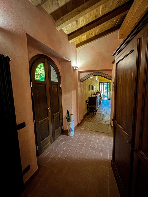 A hallway with wooden doors, a tiled floor, and a dining area in the background. - Apartment Ca' Livio (Crespiano)