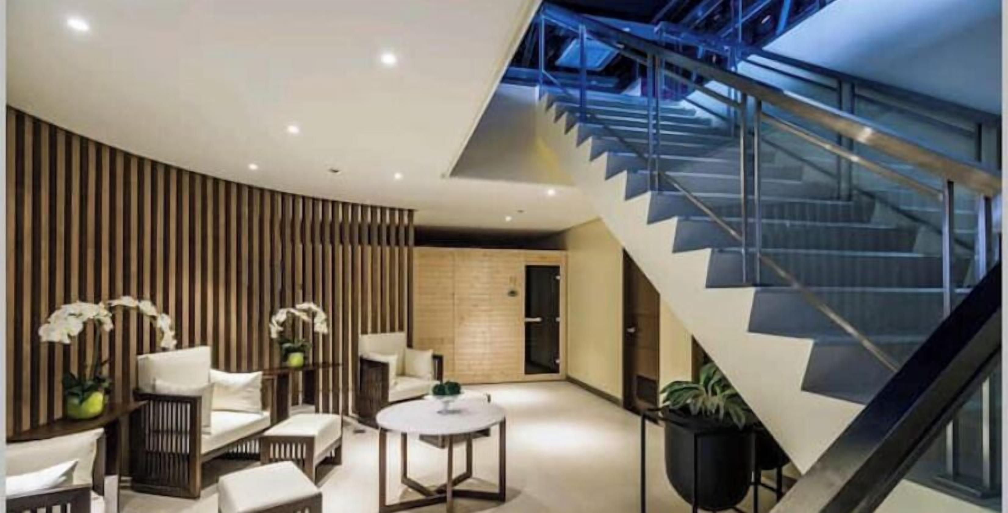 A modern interior with a curved wall, a staircase, and a seating area with white furniture.