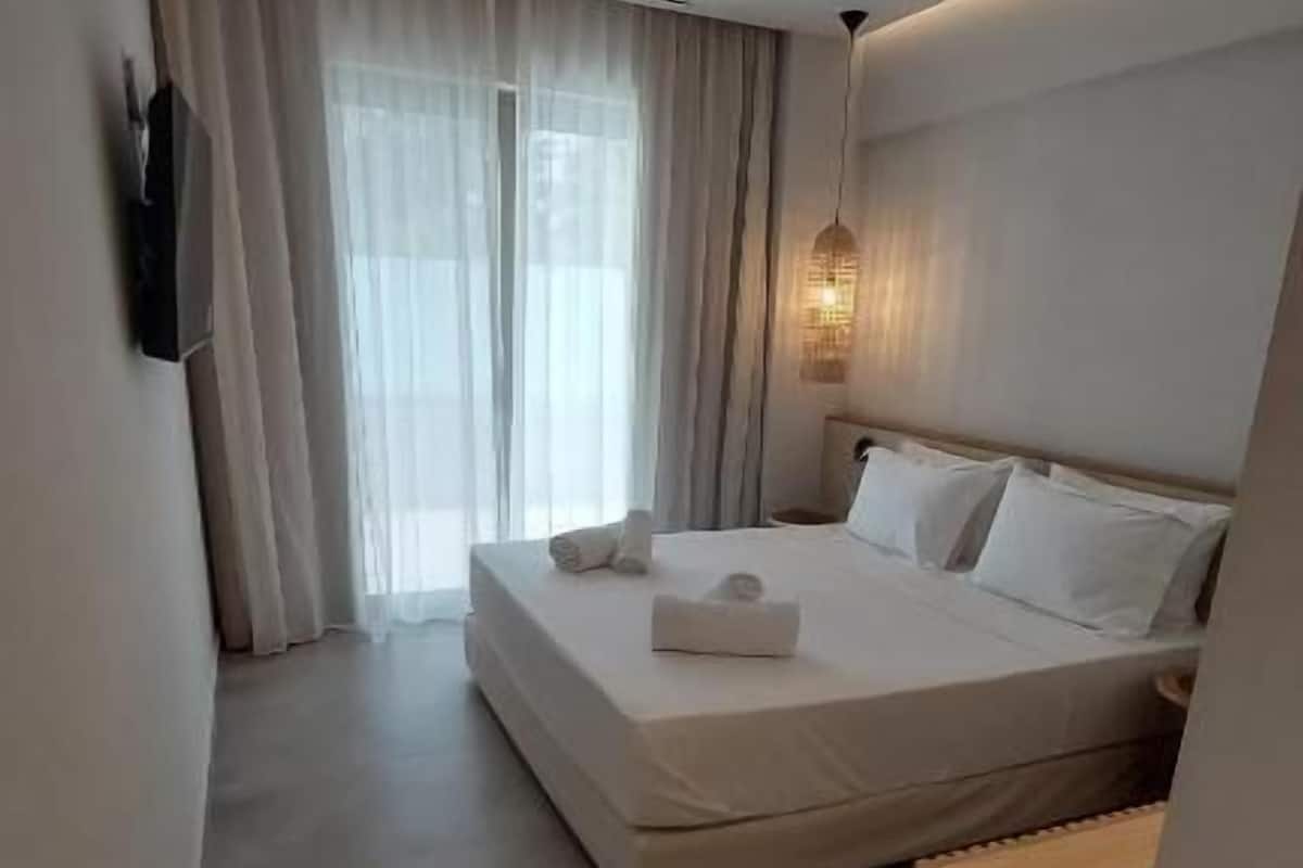 Ein modernes Hotelzimmer mit einem großen Bett, einem flachbildfernseher an der Wand und einer Deckenleuchte.