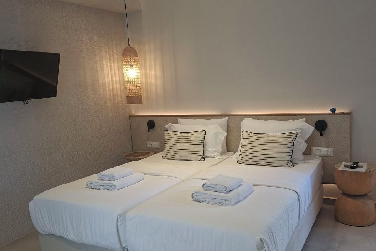 Ein modernes Schlafzimmer mit einem großen Bett, einem Flachbildfernseher und einer Pendelleuchte.