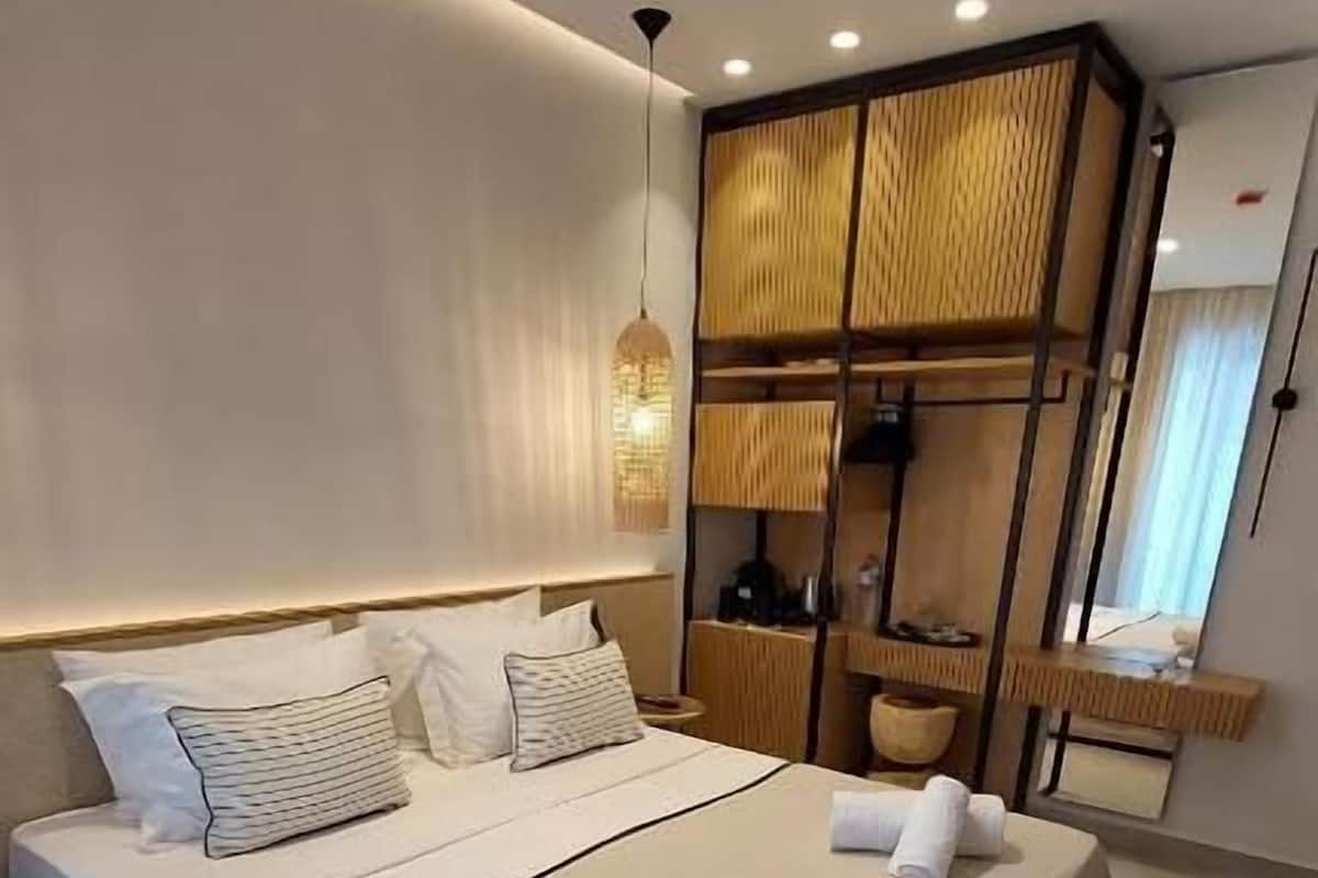 Ein modernes Schlafzimmer mit einem großen Bett, Nachttischen, einer Hängelampe und einem Holzschrank.