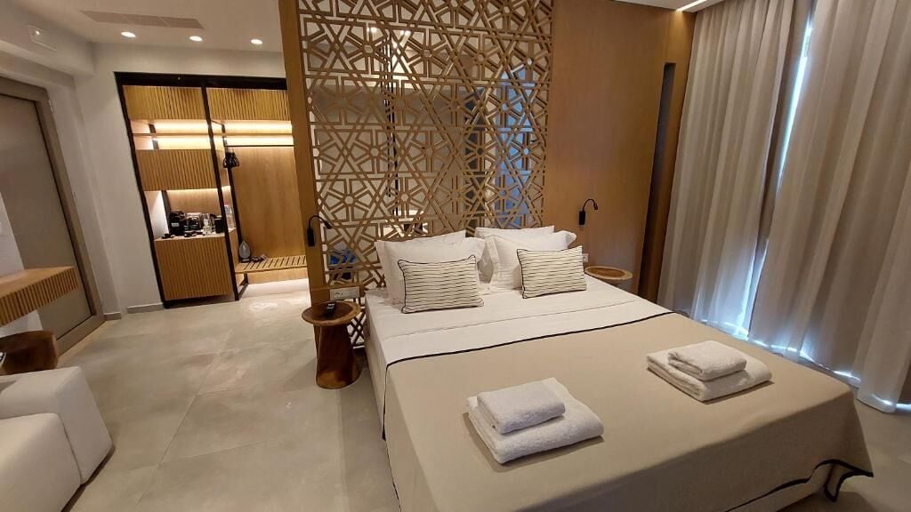 Ein modernes Hotelzimmer mit einem großen Bett, einem Schreibtisch und einem begehbaren Kleiderschrank.