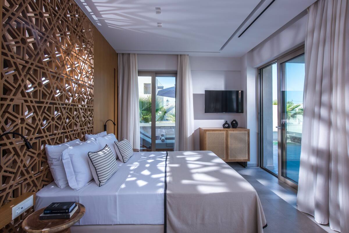 Ein modernes Hotelzimmer mit einem großen Bett, einem Fernseher und Blick auf den Ozean.