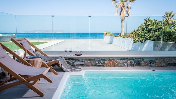 A pool area with lounge chairs and a view of the sea. - Niriides Palace (Hersonissos)