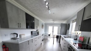 Una cocina moderna con armarios grises, una isla grande y un comedor con mesa y sillas.