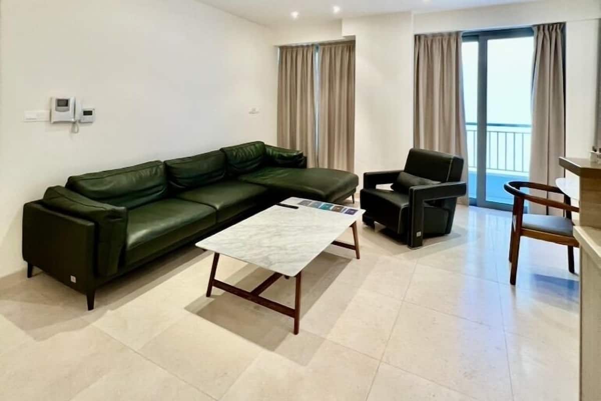 A modern living room with a sectional sofa, a coffee table, a black armchair, and a wooden side table.