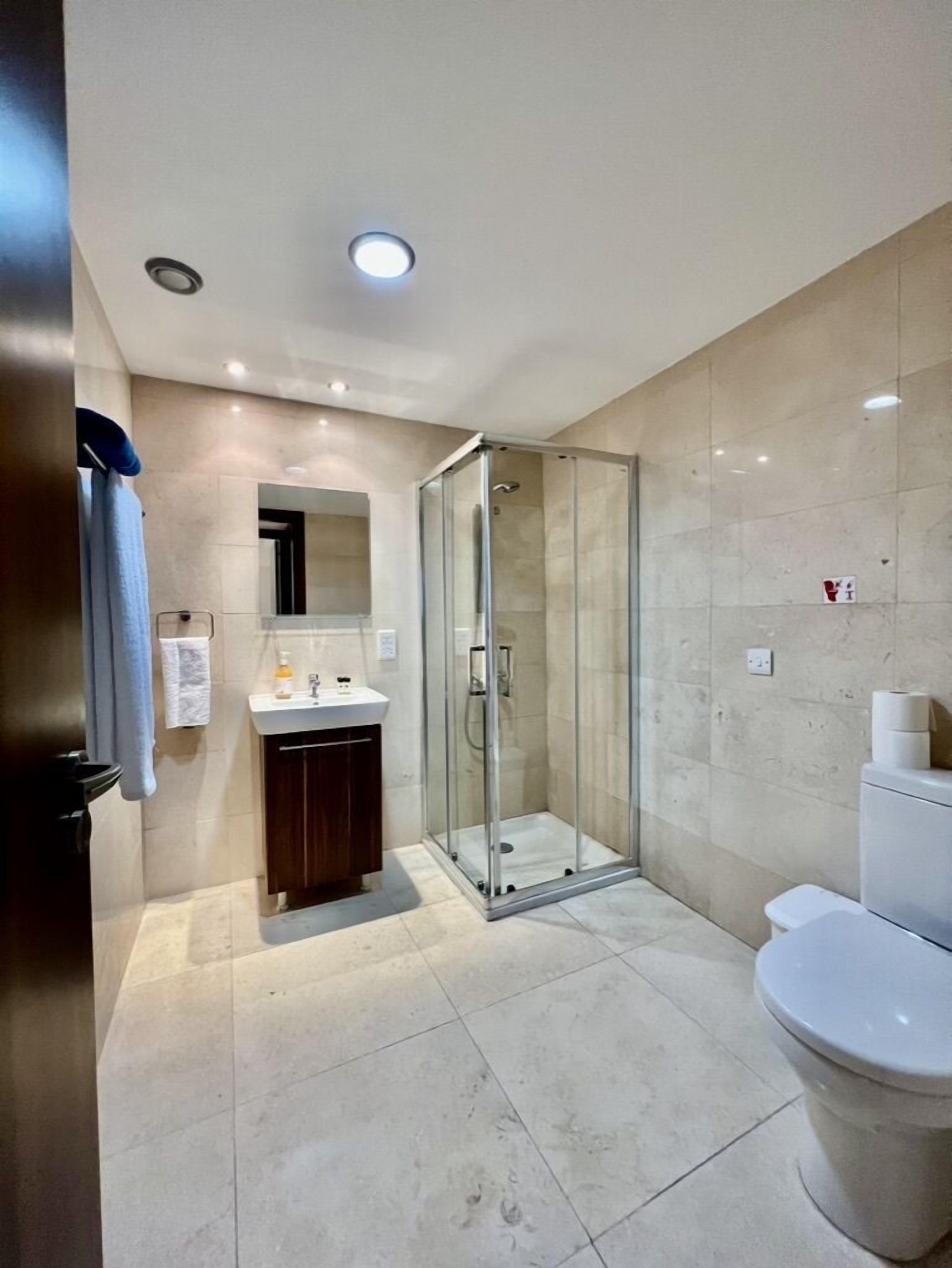 Un baño moderno con cabina de ducha de vidrio, un lavabo blanco y un inodoro.