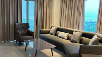 A modern living room with a sectional sofa, two side tables, and a view of the sea through large windows.
