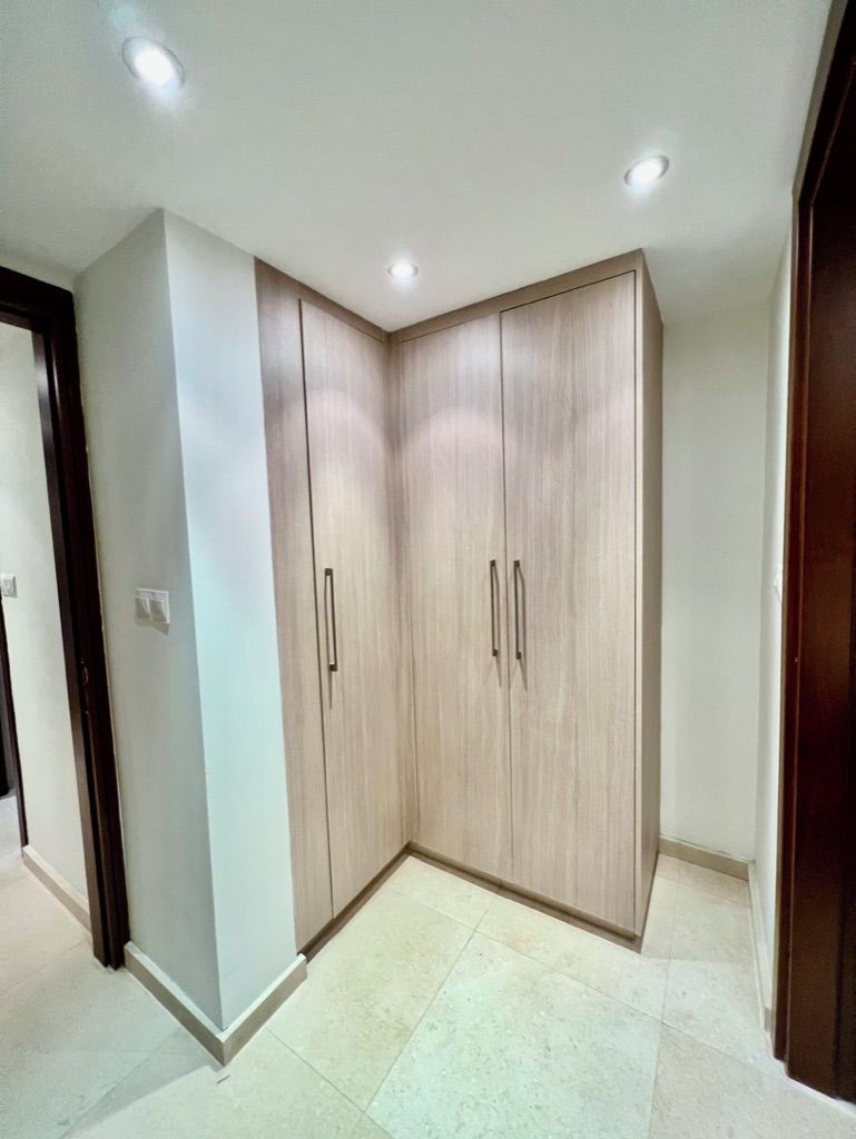 Habitación de esquina con armario, luces empotradas en el techo y suelo de baldosas.