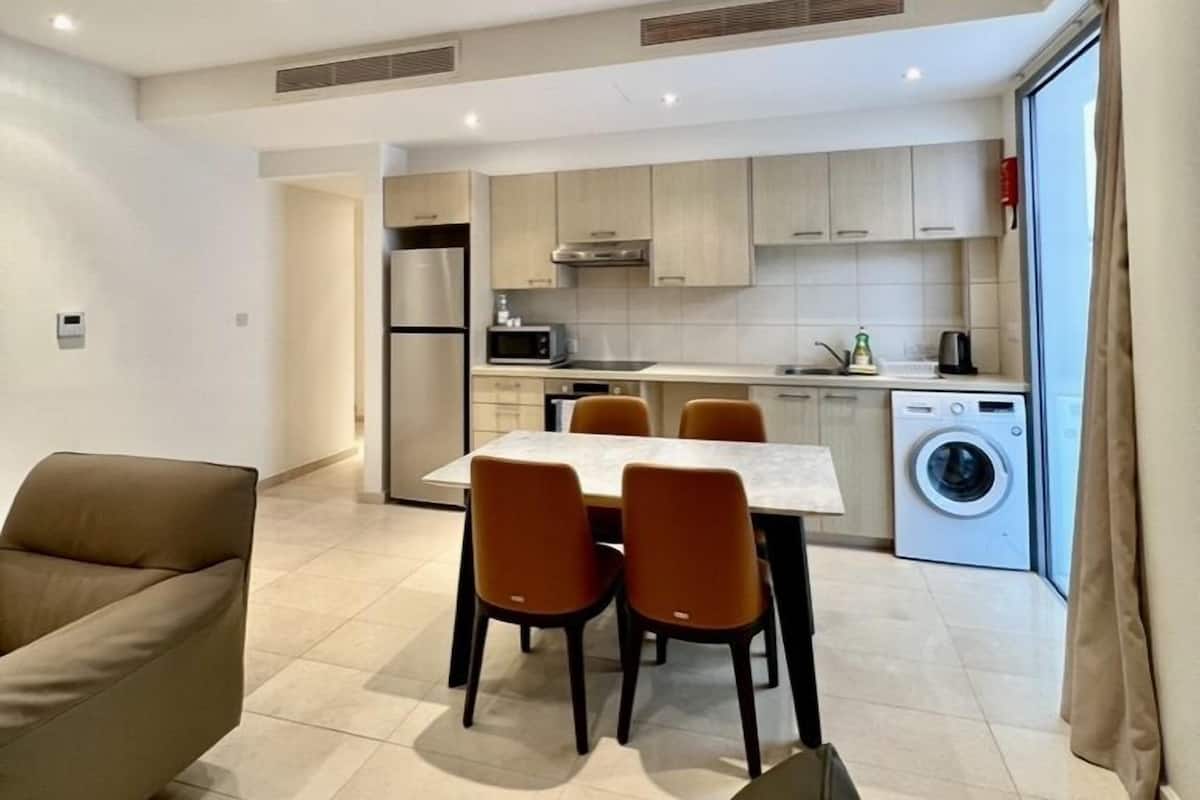 A modern apartment with a dining area, kitchen, and laundry room.