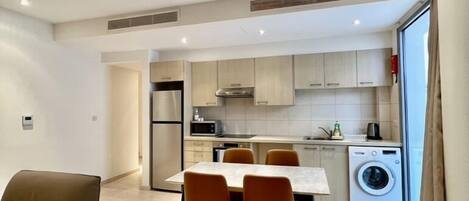 A modern apartment with a dining area, kitchen, and laundry room.