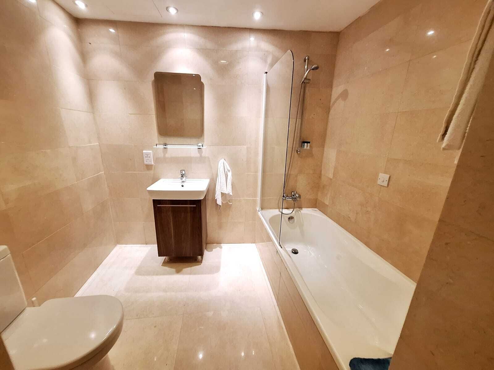A modern bathroom with a toilet, sink, vanity, and a bathtub.