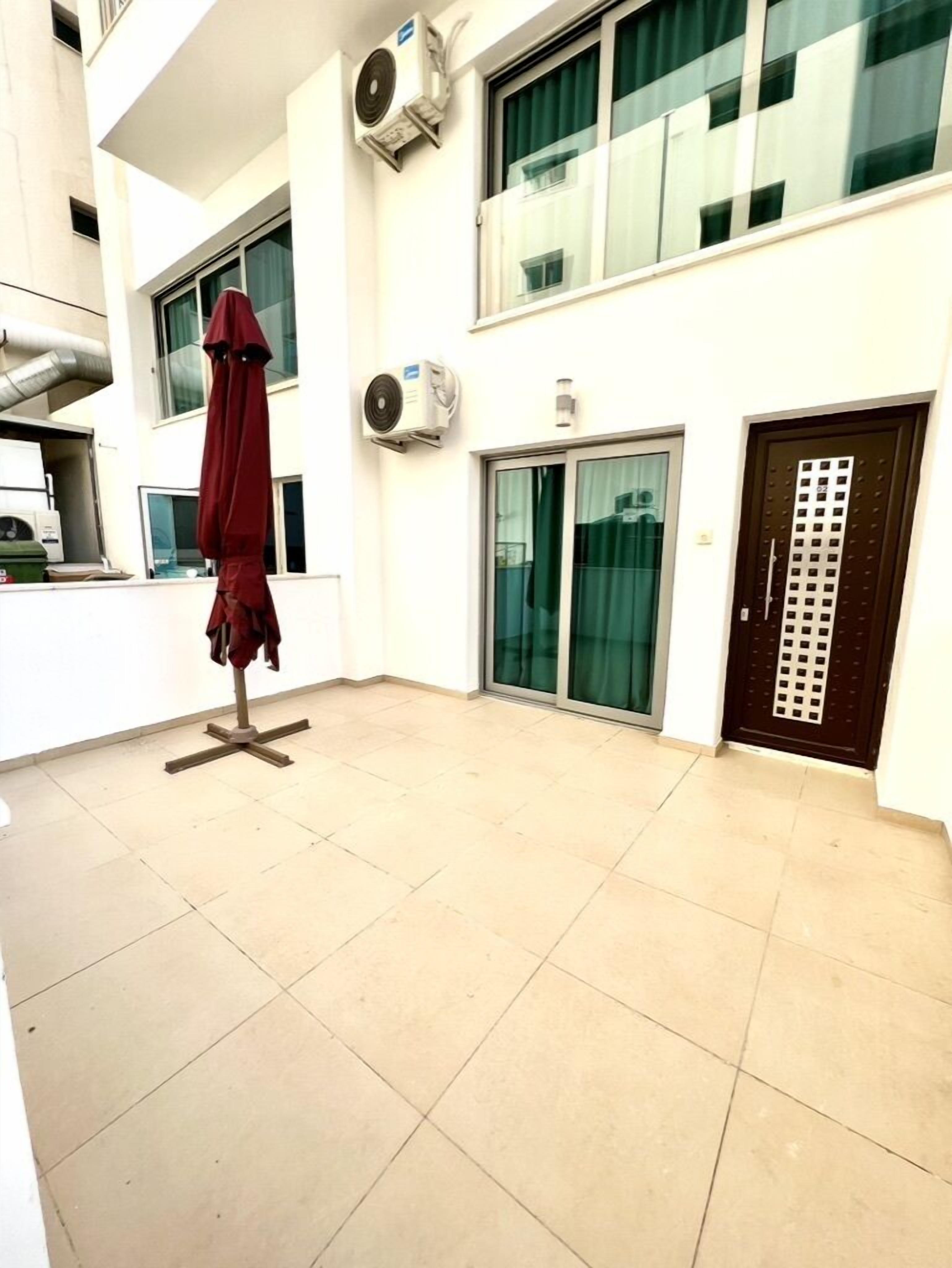 A modern building with a tiled floor, a red umbrella, and an air conditioning unit.